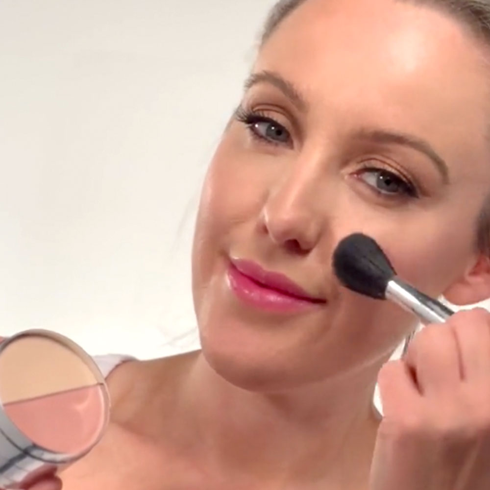 woman applying makeup with a powder brush