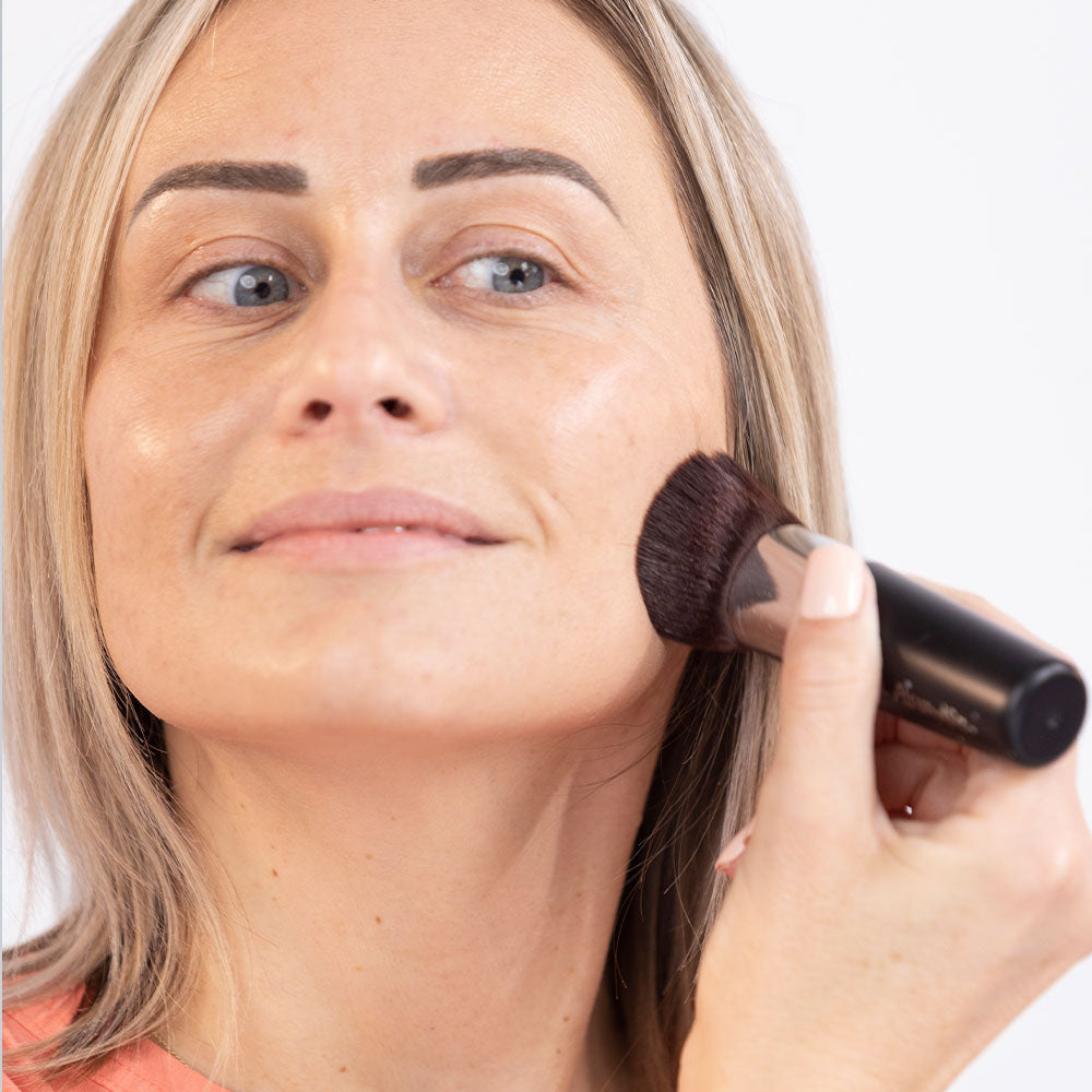 woman applying foundation with a kabuki brush